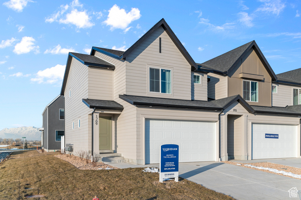 View of front facade with a garage, a front yard, and concrete driveway