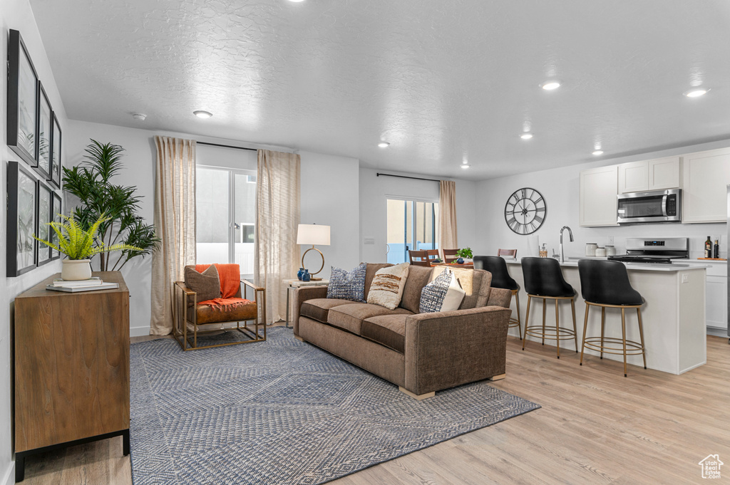 Living room featuring recessed lighting, a textured ceiling, and light wood-style floors