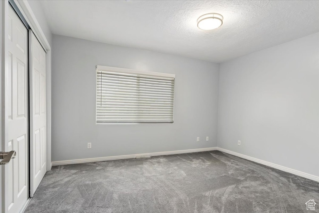 Unfurnished bedroom with a closet, baseboards, carpet flooring, and a textured ceiling