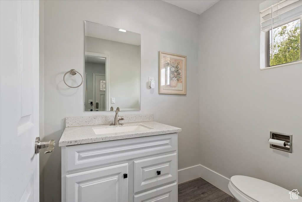 Bathroom with toilet, baseboards, wood finished floors, and vanity