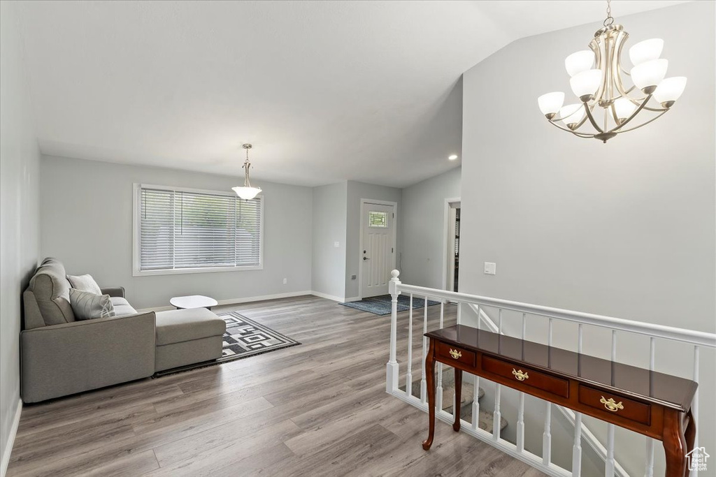Living room with baseboards, an inviting chandelier, wood finished floors, and vaulted ceiling