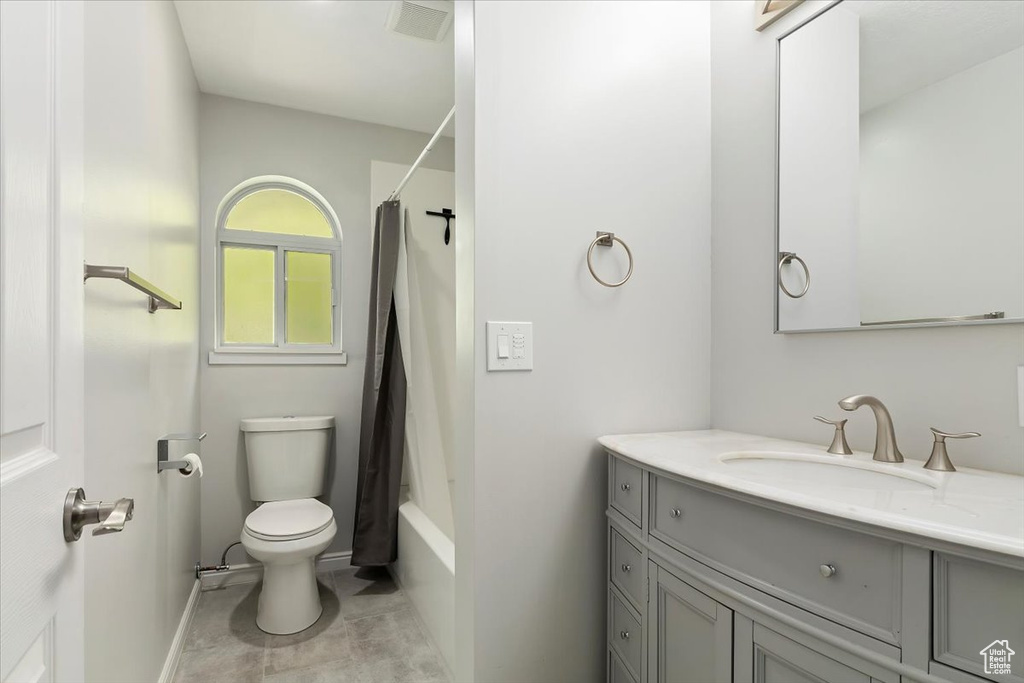 Bathroom with visible vents, shower / tub combo with curtain, vanity, toilet, and baseboards