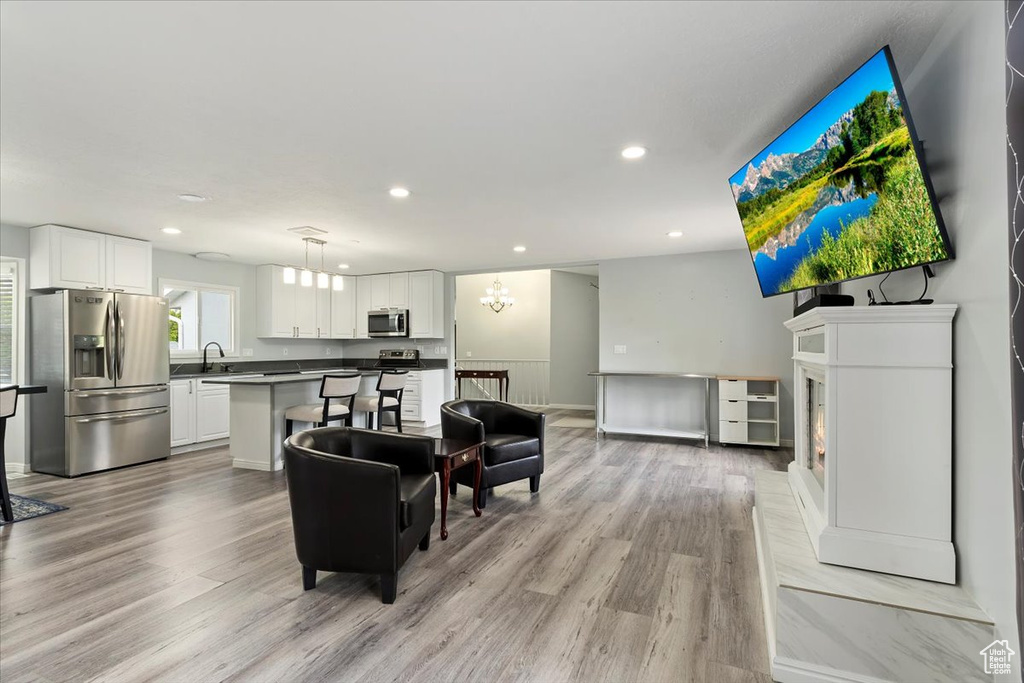 Living room with recessed lighting, a glass covered fireplace, and light wood finished floors