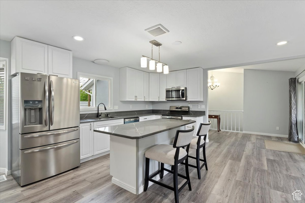 Kitchen featuring visible vents, light wood-type flooring, a sink, stainless steel appliances, and white cabinetry