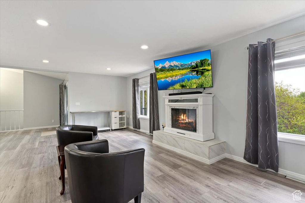 Living area featuring visible vents, recessed lighting, wood finished floors, and a warm lit fireplace