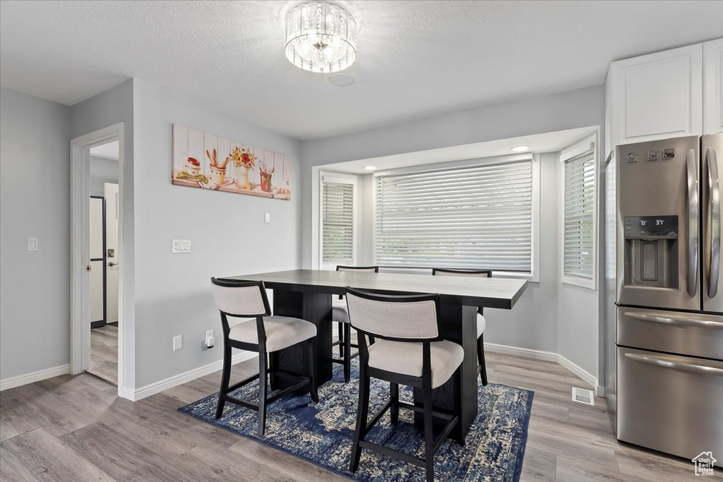 Dining area with baseboards, light wood finished floors, and a notable chandelier