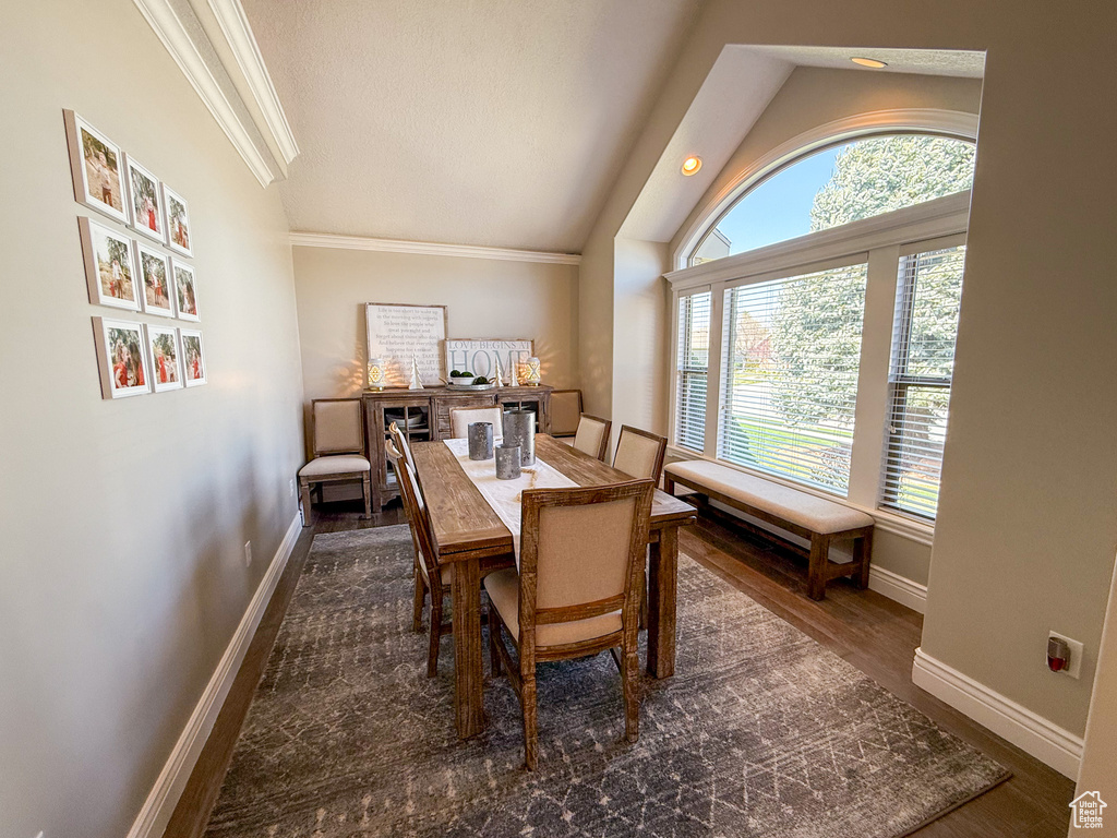 Dining area featuring baseboards, vaulted ceiling, ornamental molding, and dark wood-type flooring