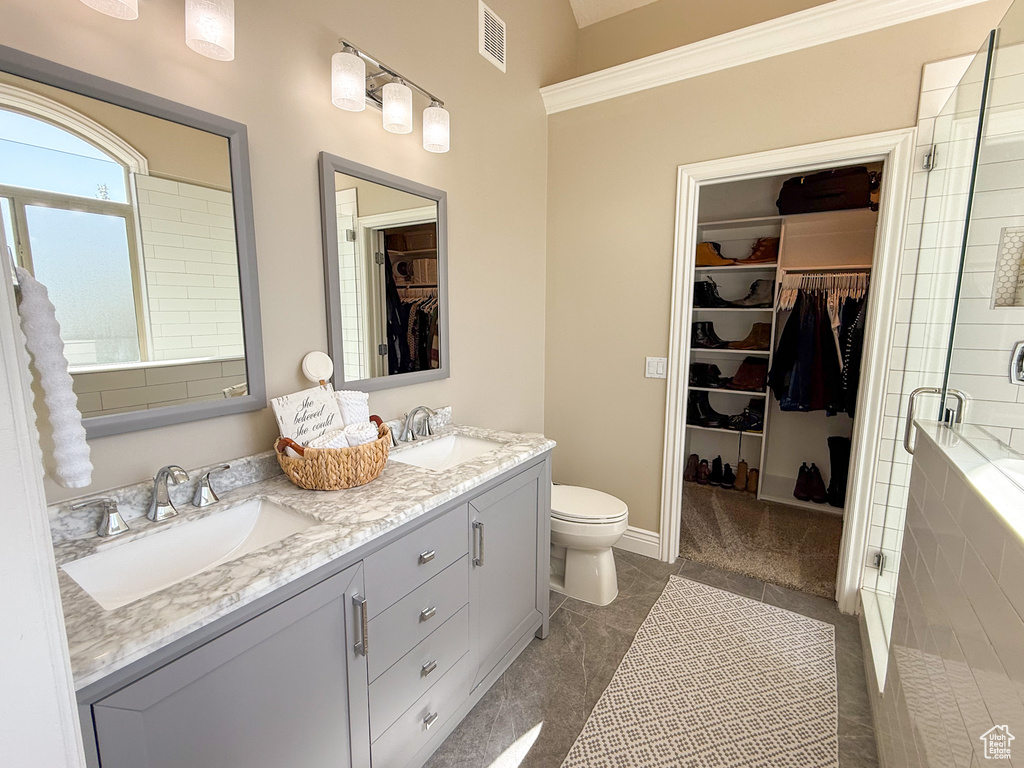 Full bathroom featuring visible vents, a sink, double vanity, and a shower stall