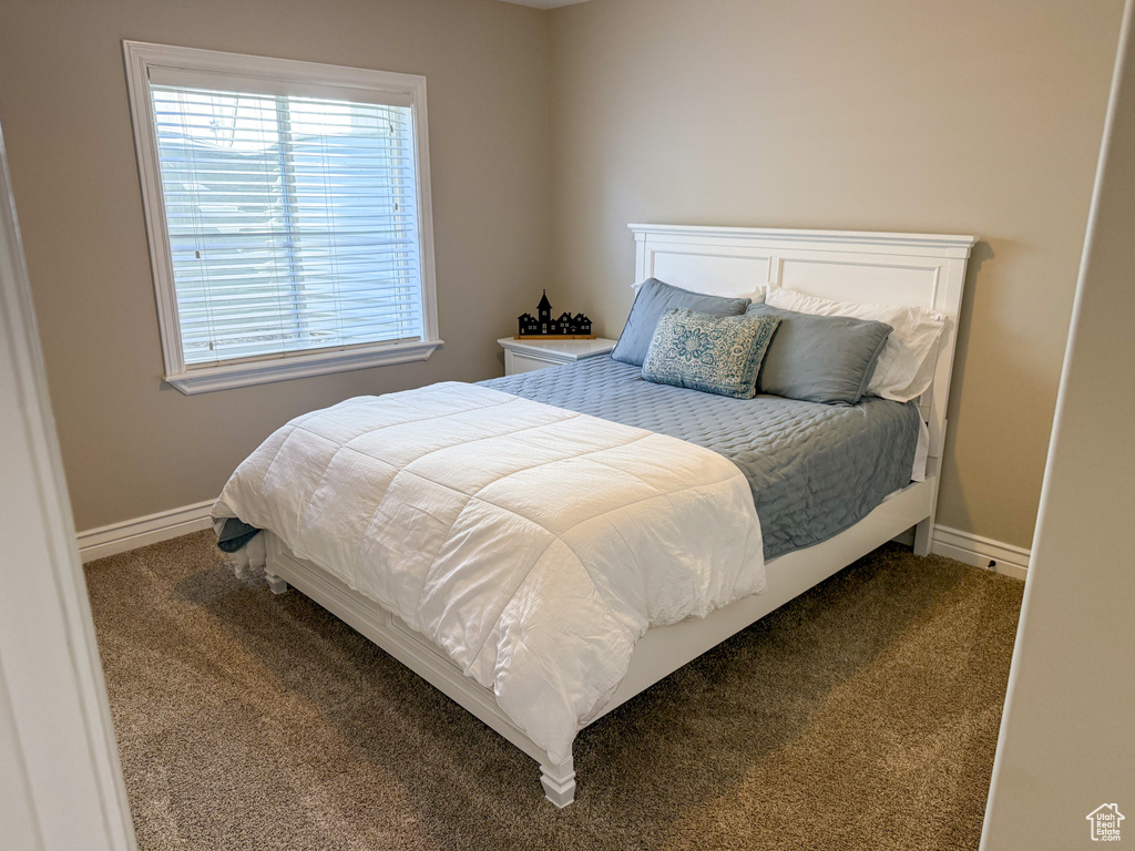 Bedroom featuring baseboards and dark carpet