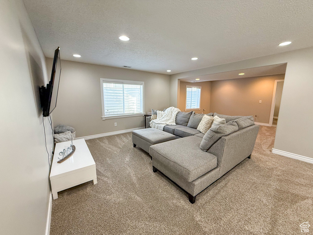 Living room with recessed lighting, a textured ceiling, baseboards, and light carpet