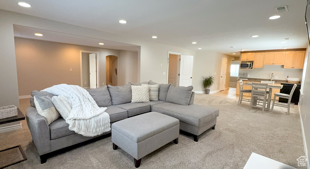 Living room featuring recessed lighting, arched walkways, baseboards, and light carpet