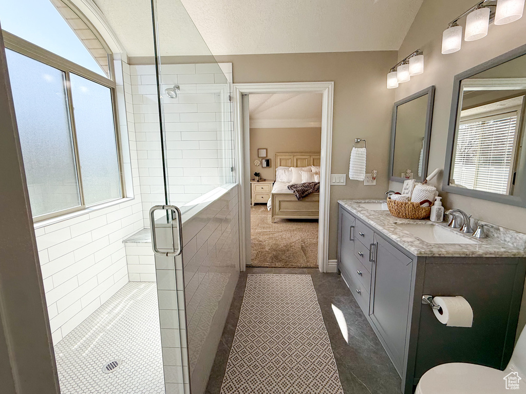 Ensuite bathroom featuring double vanity, vaulted ceiling, a stall shower, a sink, and ensuite bathroom