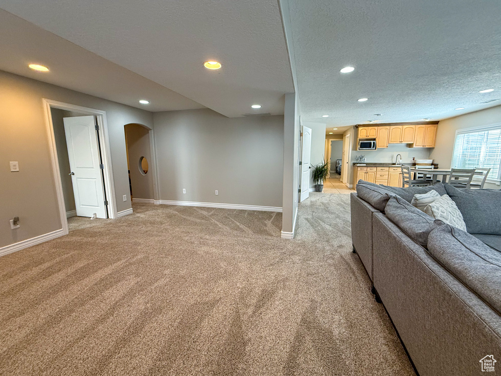 Living area with baseboards, arched walkways, recessed lighting, and light colored carpet