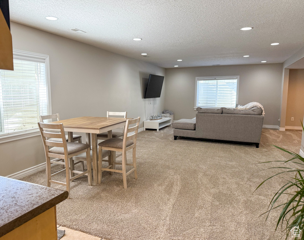 Dining area featuring baseboards, light carpet, recessed lighting, and a textured ceiling