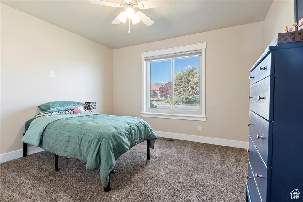 Carpeted bedroom featuring baseboards, ceiling fan, and visible vents