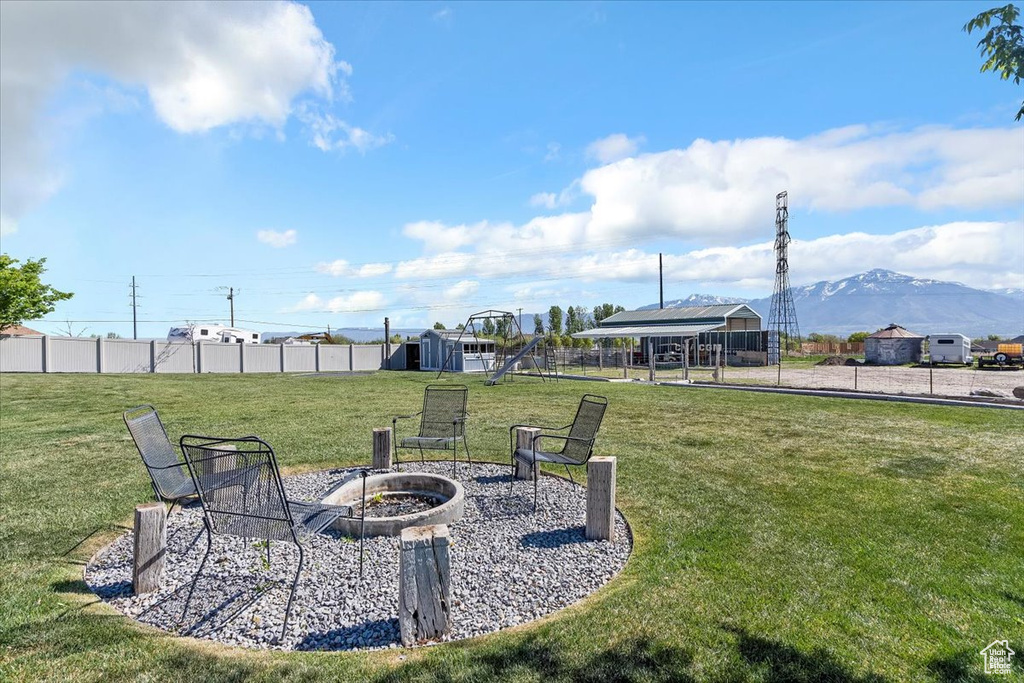 View of yard with a detached carport, a fire pit, fence, and a mountain view