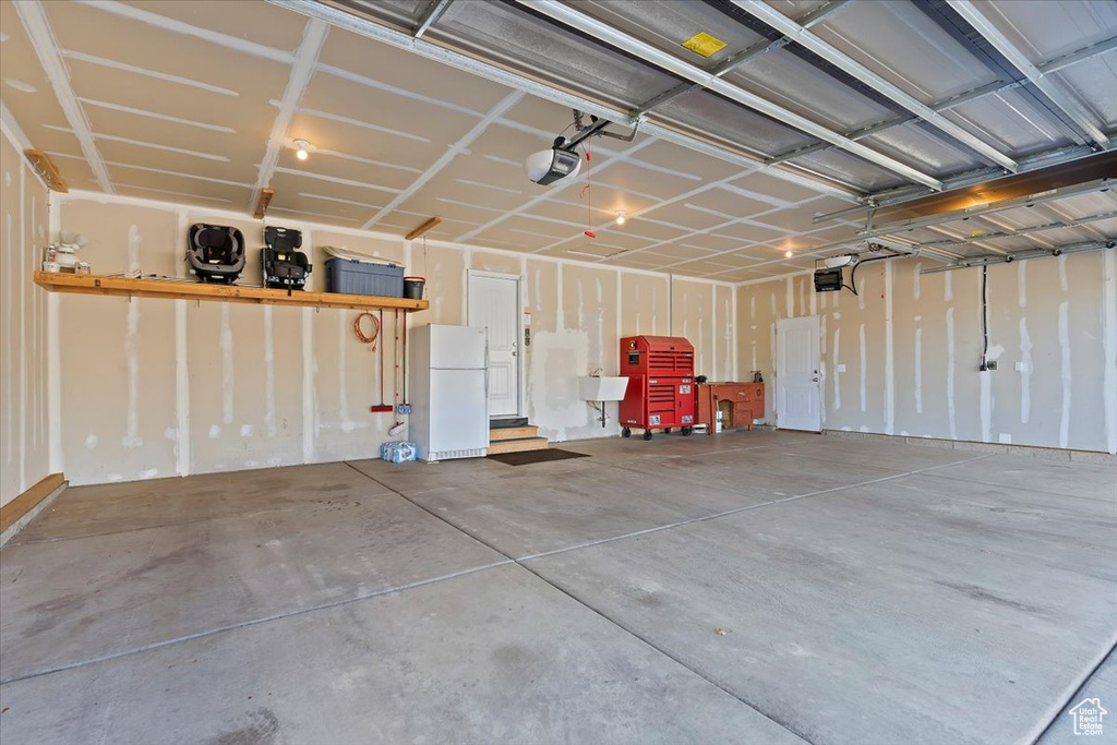 Garage featuring a sink, freestanding refrigerator, and a garage door opener
