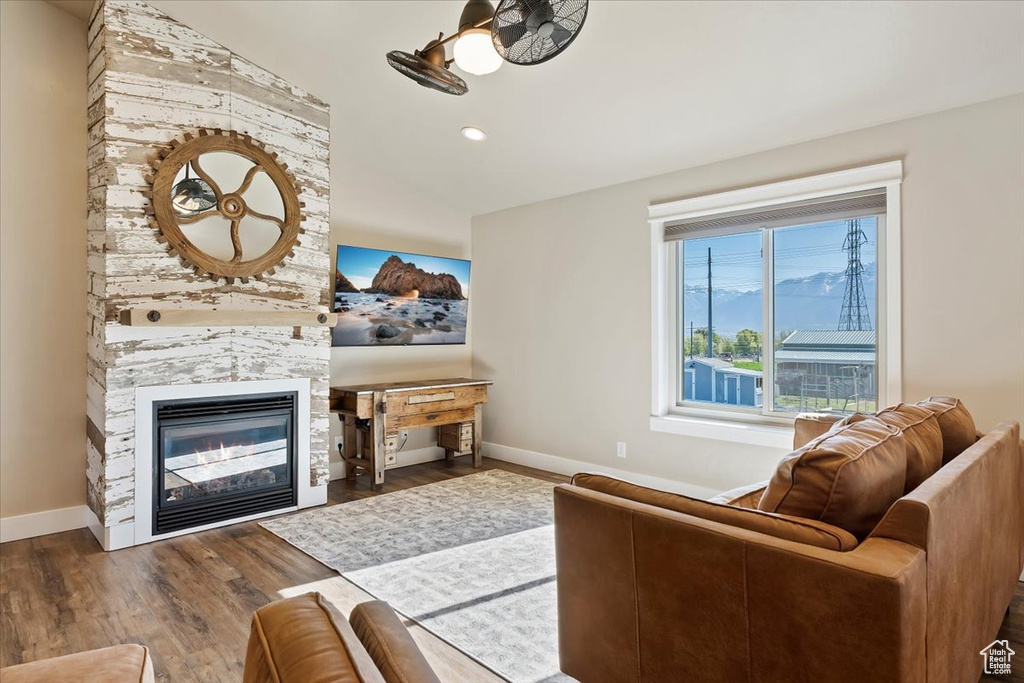Living room featuring baseboards, a stone fireplace, and wood finished floors