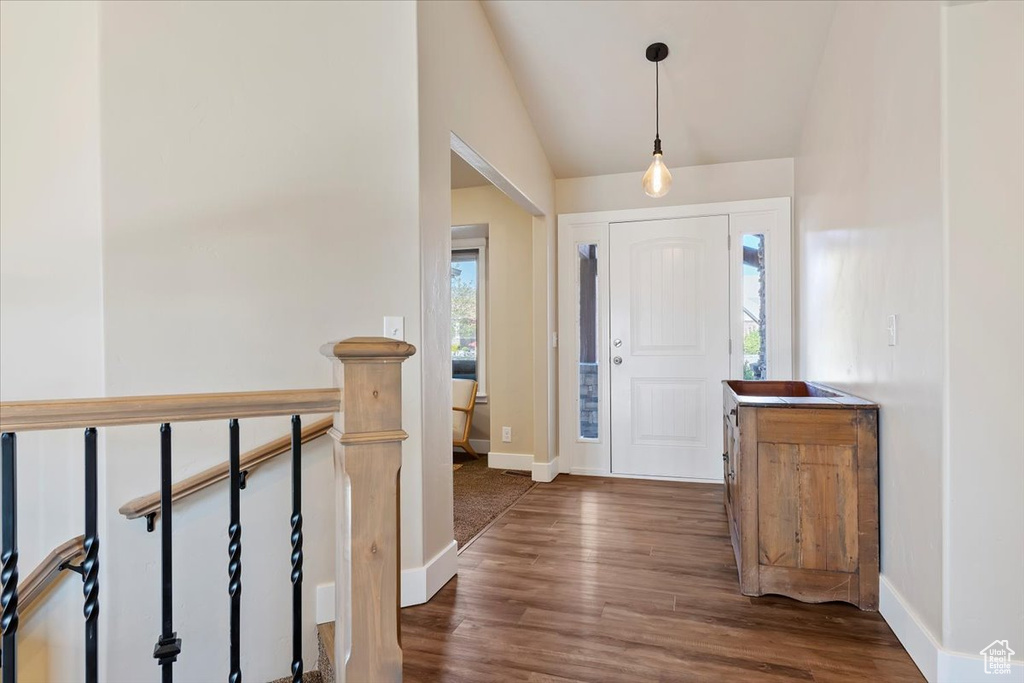 Foyer entrance with wood finished floors, baseboards, and lofted ceiling