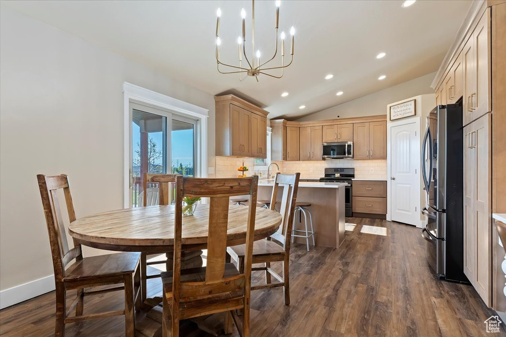 Dining space with dark wood-style flooring, a notable chandelier, recessed lighting, and lofted ceiling