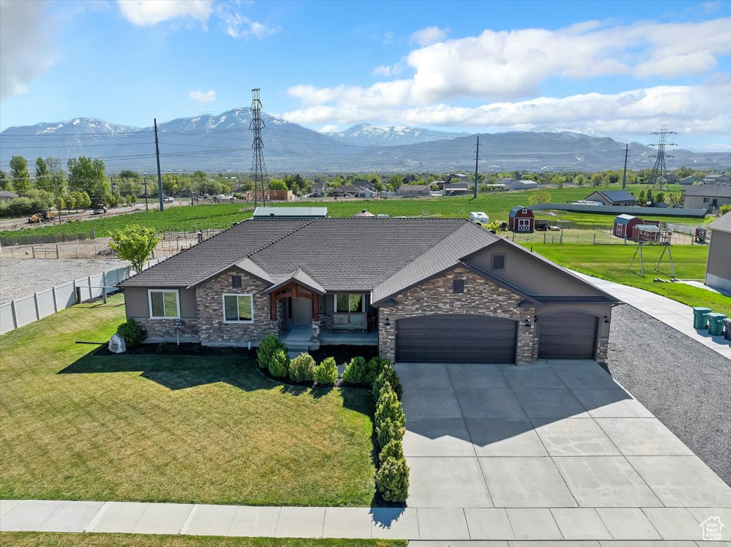 View of front of house featuring fence, an attached garage, stone siding, a mountain view, and concrete driveway