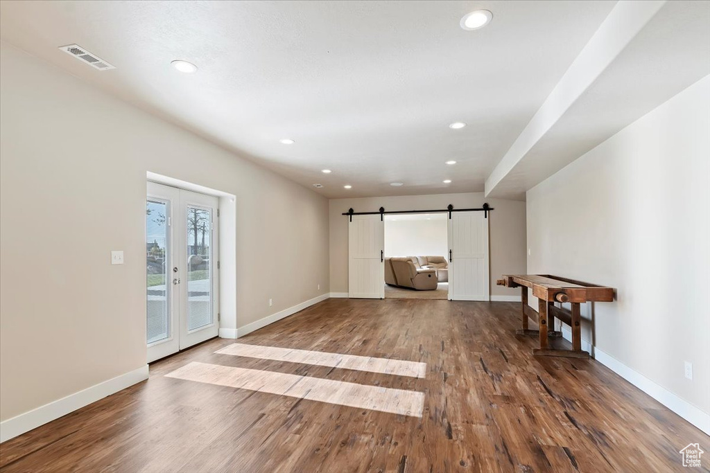 Unfurnished living room featuring french doors, visible vents, a barn door, baseboards, and recessed lighting