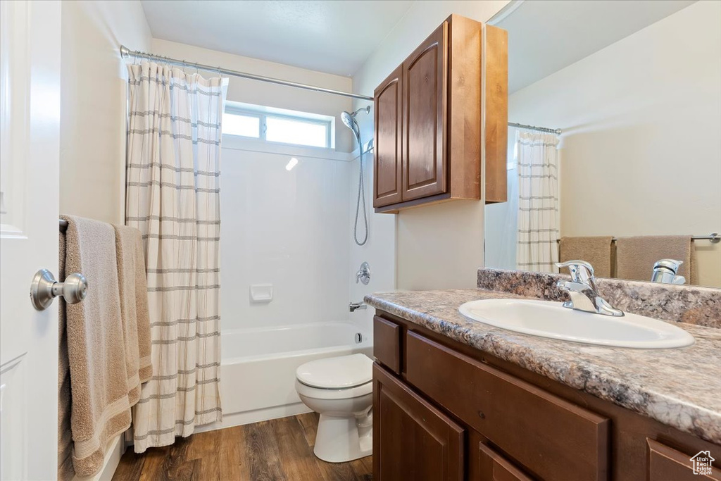 Full bathroom featuring toilet, wood finished floors, shower / bath combo, and vanity
