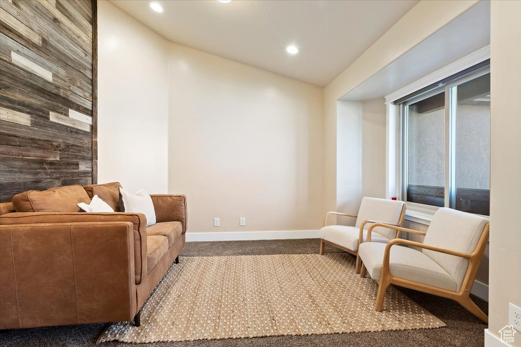 Living area with carpet flooring, wooden walls, recessed lighting, baseboards, and vaulted ceiling