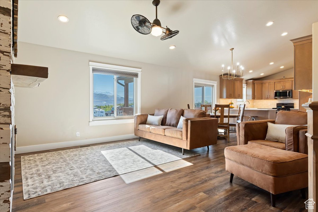 Living room with recessed lighting, dark wood-style flooring, a chandelier, and vaulted ceiling