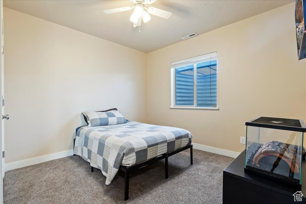 Carpeted bedroom with a ceiling fan, baseboards, and visible vents