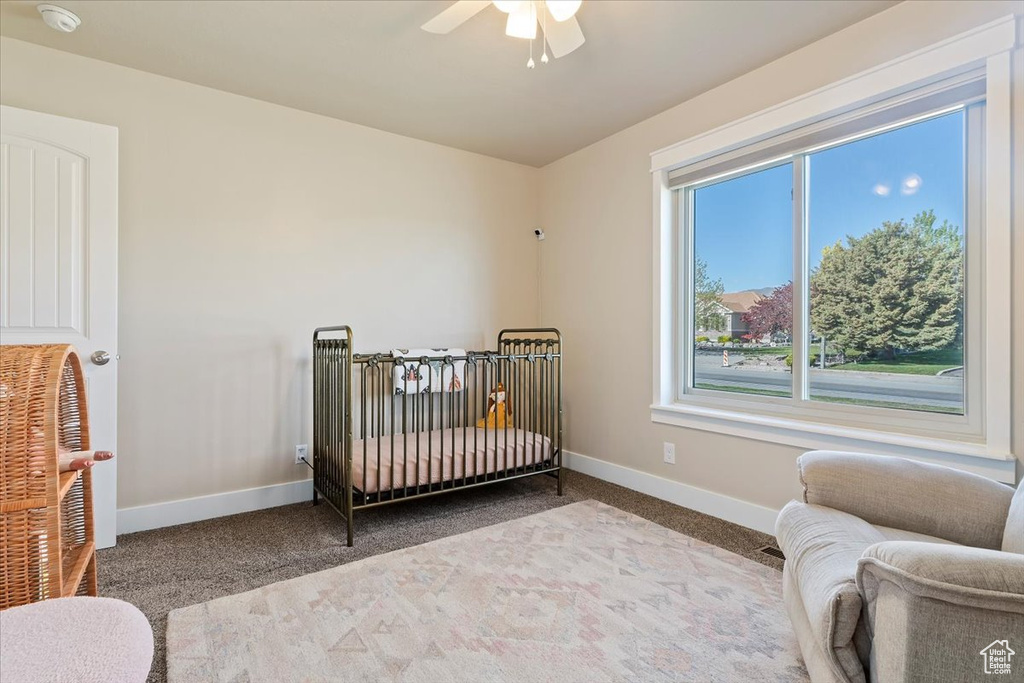 Bedroom featuring baseboards, ceiling fan, carpet, and a nursery area