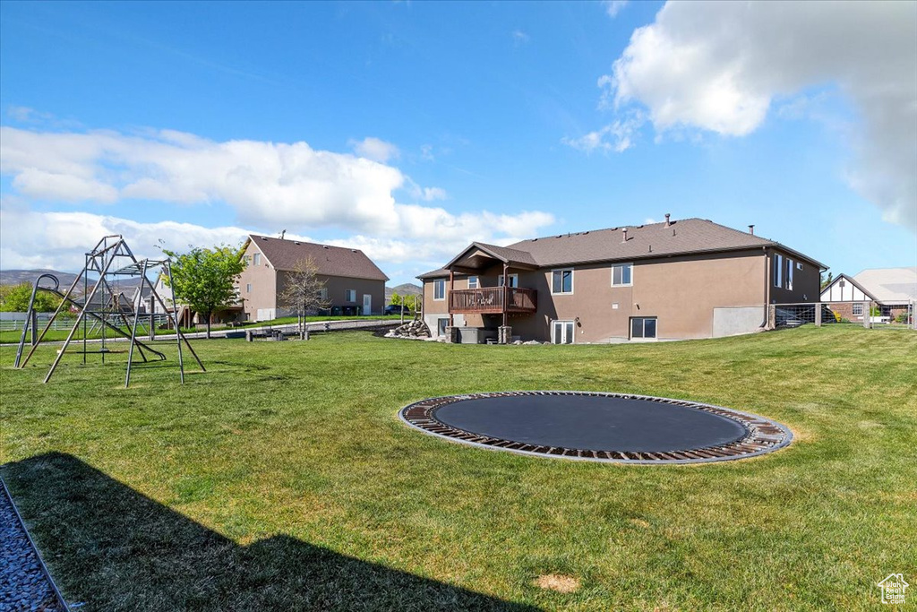 View of yard with a trampoline, a playground, and central AC