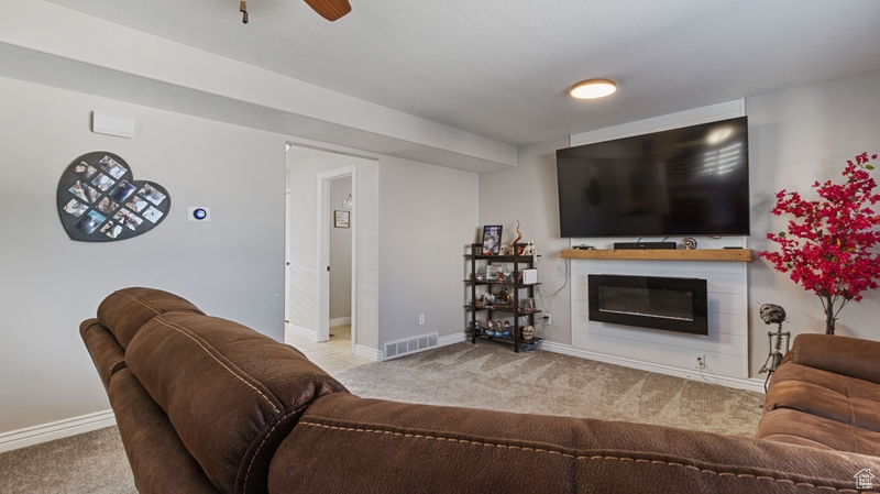 Living area featuring a glass covered fireplace, baseboards, carpet, and visible vents