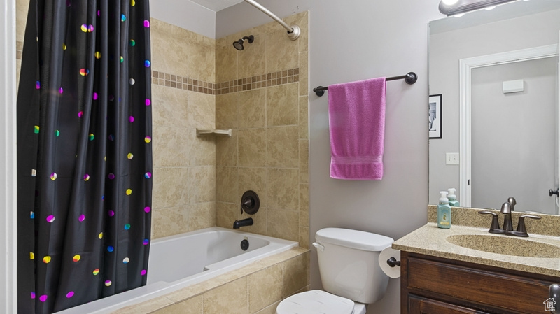 Bathroom featuring vanity, toilet, and tiled shower / bath combo
