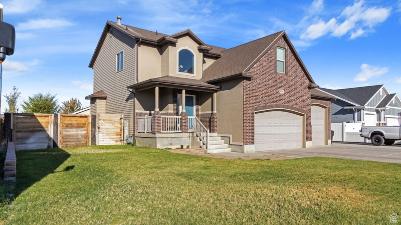 Traditional-style house with a front lawn, fence, stucco siding, brick siding, and driveway