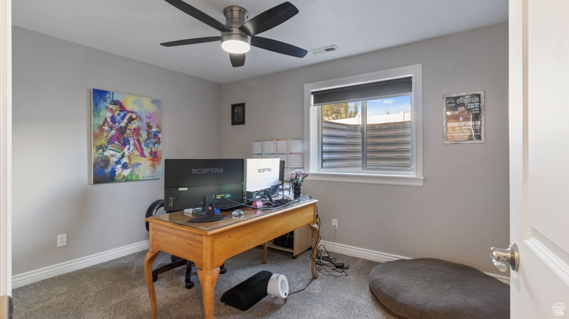 Carpeted office featuring baseboards, ceiling fan, and visible vents