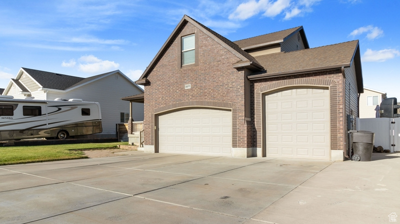 View of front facade with a garage, concrete driveway, and brick siding