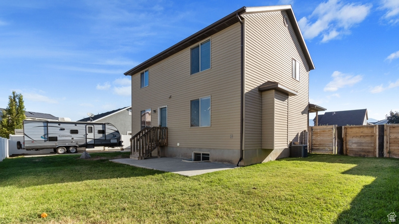 Rear view of house with central AC, fence, a yard, and a patio