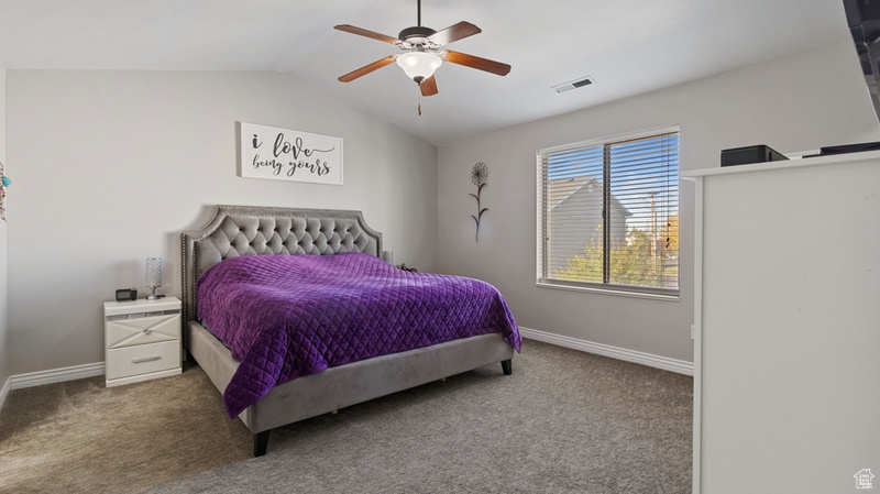 Bedroom with carpet flooring, ceiling fan, baseboards, vaulted ceiling, and visible vents
