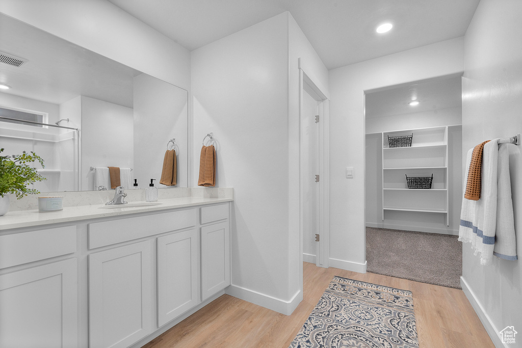 Bathroom featuring visible vents, baseboards, wood finished floors, and vanity