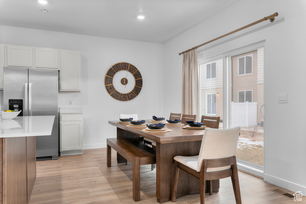 Dining area featuring visible vents, light wood-style flooring, baseboards, and a wealth of natural light