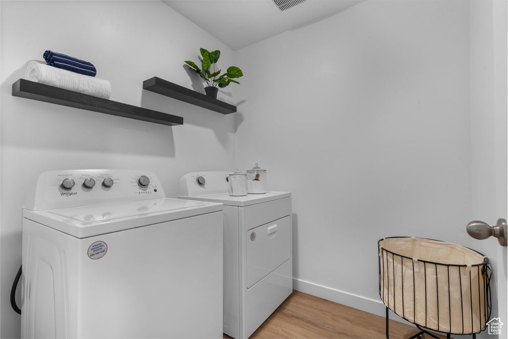 Laundry room with laundry area, light wood finished floors, baseboards, and washing machine and clothes dryer