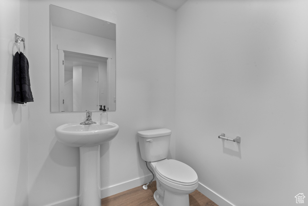 Bathroom with baseboards, a sink, wood finished floors, and toilet