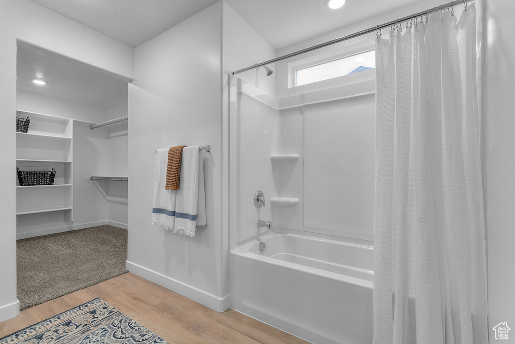 Bathroom with shower / bathtub combination with curtain, wood finished floors, baseboards, a spacious closet, and recessed lighting