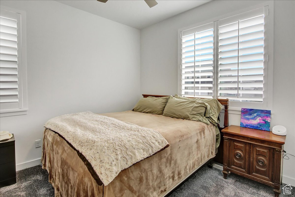 Bedroom with dark carpet, a ceiling fan, and baseboards