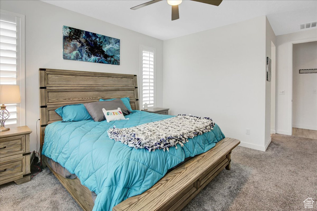 Carpeted bedroom featuring visible vents, a ceiling fan, and baseboards