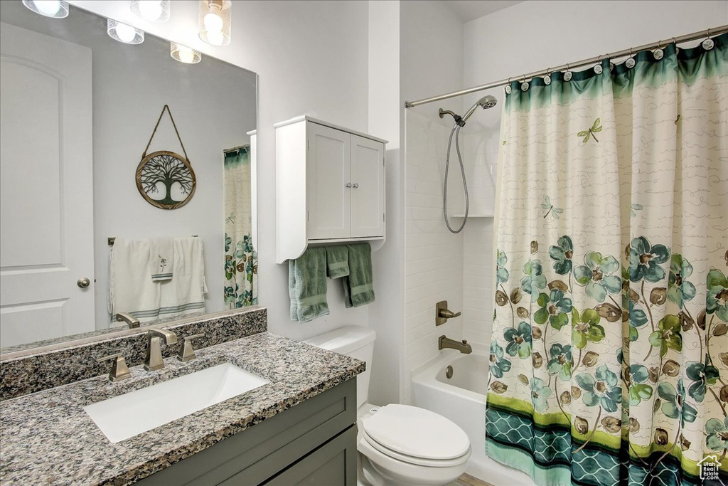 Bathroom with vanity, toilet, and shower / tub combo with curtain