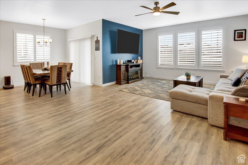 Living area with baseboards, light wood finished floors, and ceiling fan with notable chandelier
