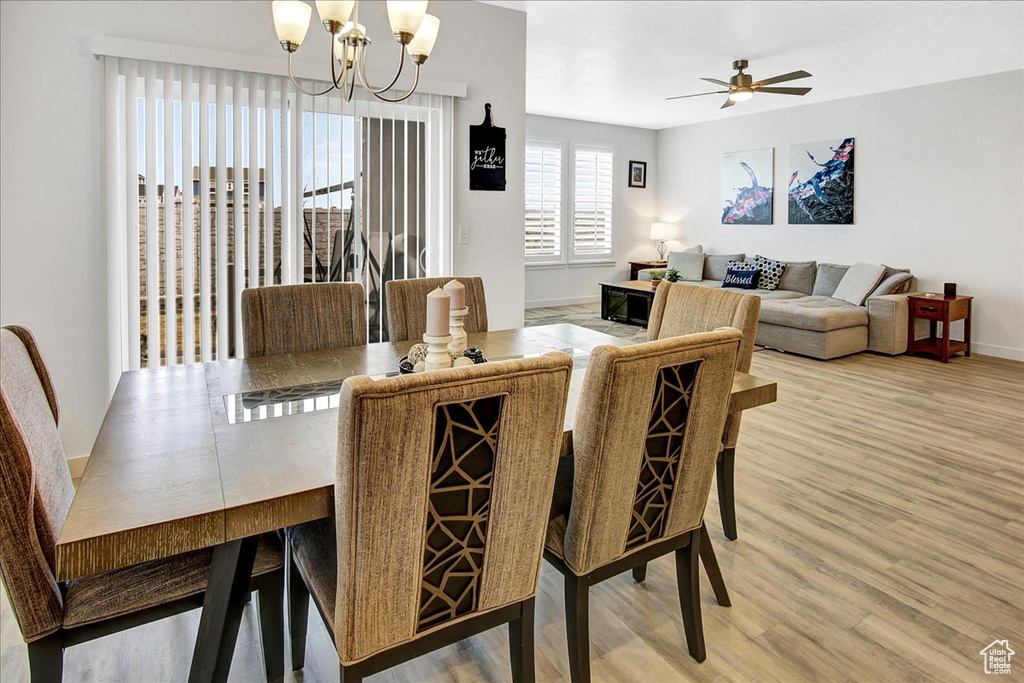 Dining space featuring baseboards, ceiling fan with notable chandelier, and light wood finished floors