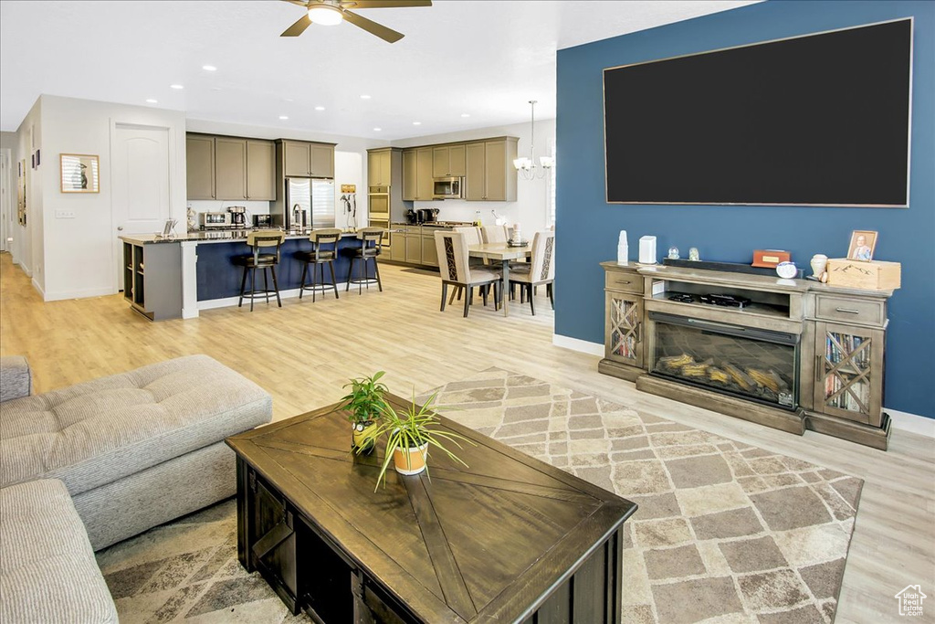 Living room featuring ceiling fan, baseboards, and light wood-type flooring